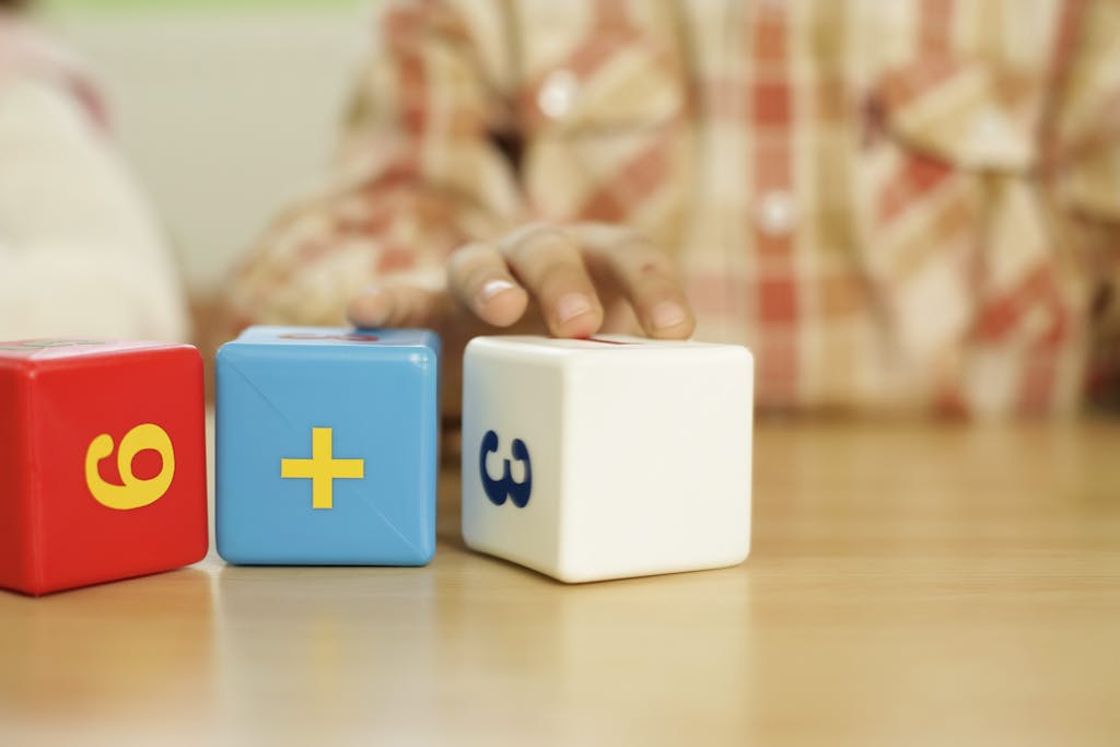 Close-up of child's hand touching educational math blocks on desk.