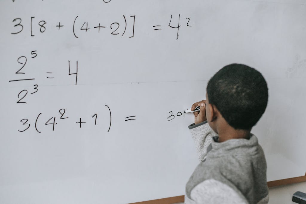 Focused child solving equations on a whiteboard, showcasing education and problem-solving skills.